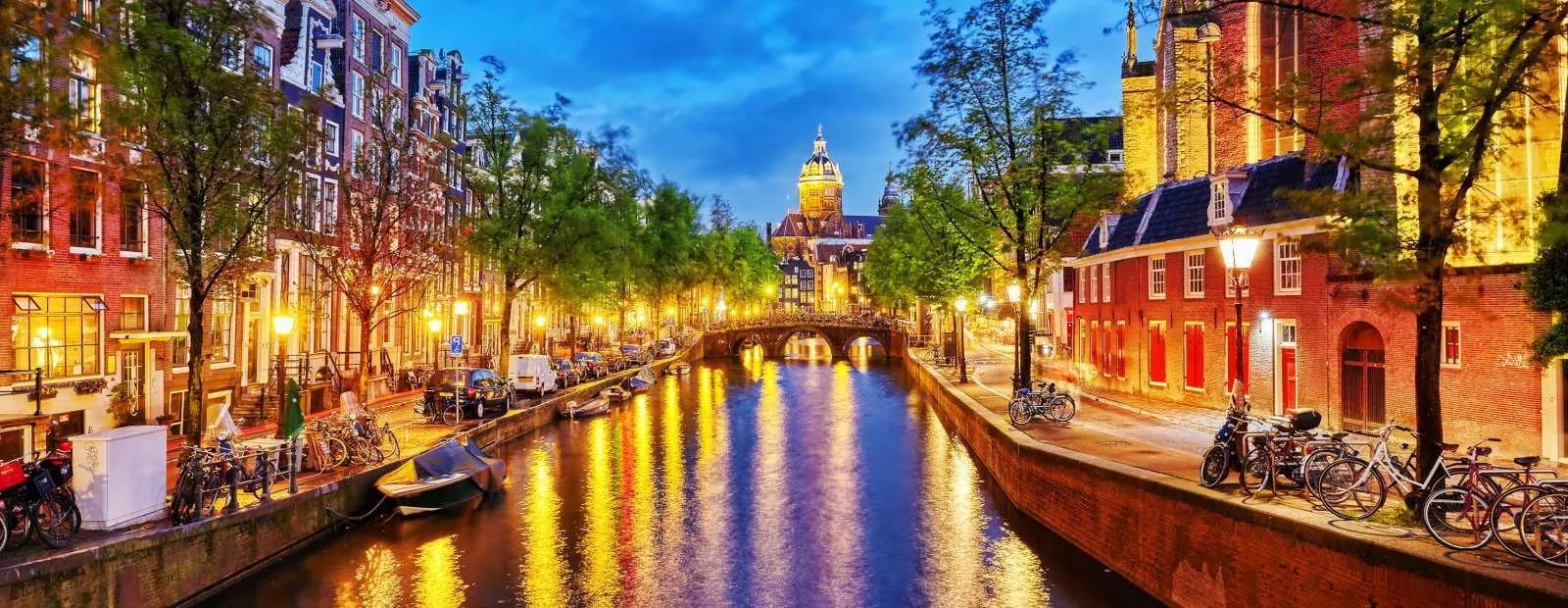 Amsterdam canal nightlife scene with glowing lights – perfect destination for a stag weekend in Amsterdam